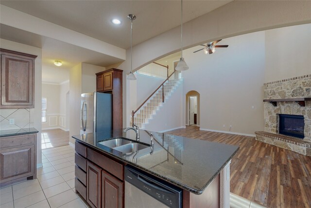 kitchen featuring ceiling fan, sink, a kitchen island with sink, a fireplace, and appliances with stainless steel finishes