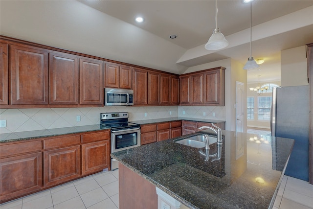 kitchen with an inviting chandelier, a center island with sink, sink, decorative backsplash, and appliances with stainless steel finishes