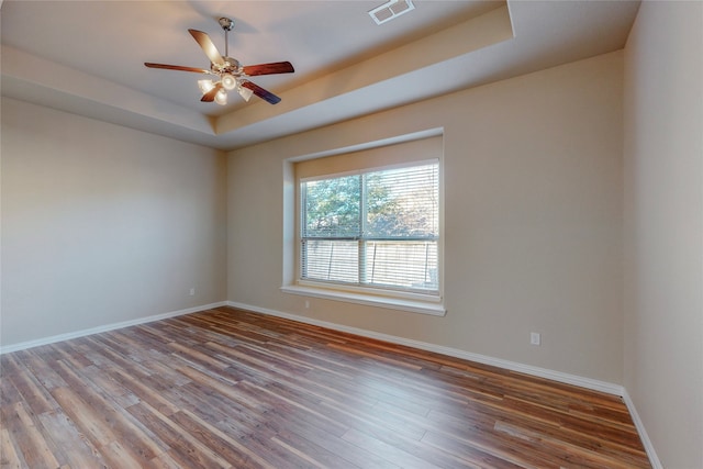 spare room with hardwood / wood-style flooring, ceiling fan, and a tray ceiling