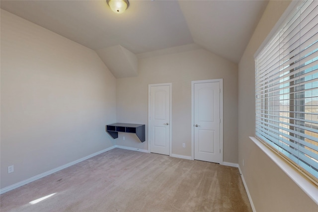 unfurnished bedroom featuring light carpet and vaulted ceiling