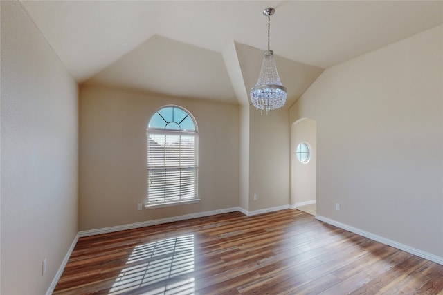 empty room with wood-type flooring, vaulted ceiling, and a notable chandelier