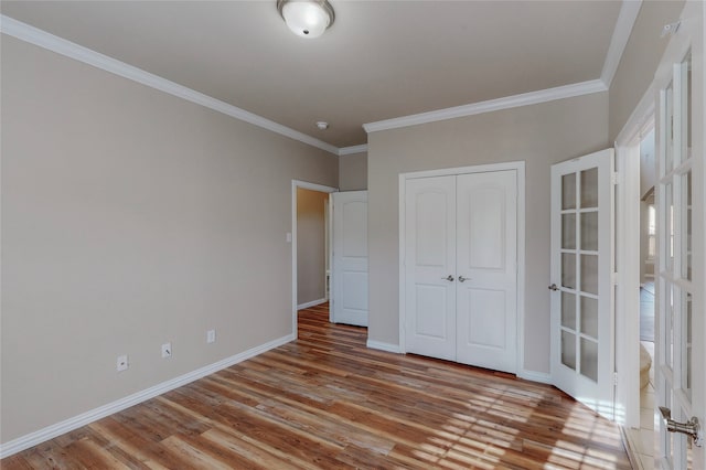 unfurnished bedroom with crown molding, french doors, light hardwood / wood-style flooring, and a closet