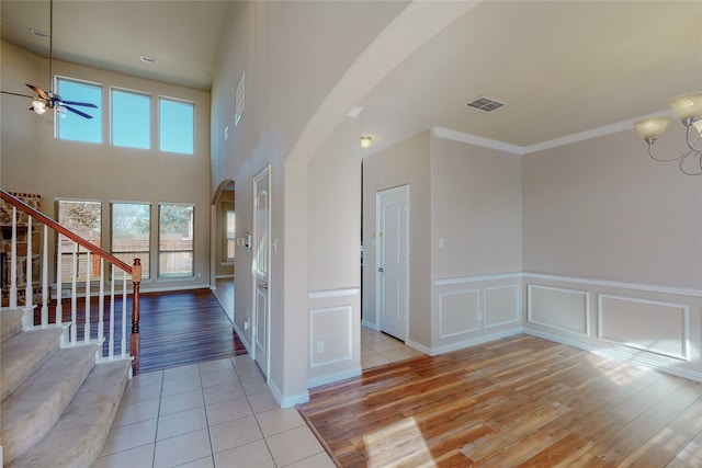 entrance foyer with light wood-type flooring, ceiling fan with notable chandelier, and crown molding