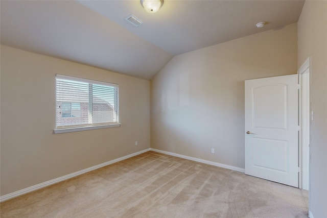 carpeted spare room featuring vaulted ceiling