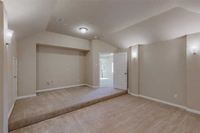 additional living space featuring light colored carpet and lofted ceiling