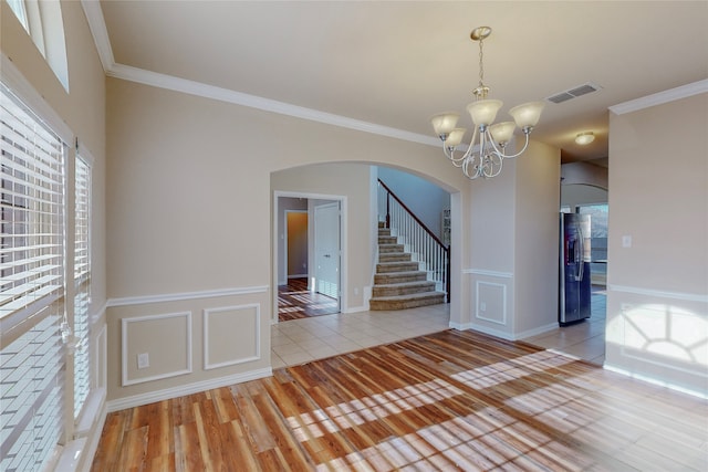 unfurnished room with light hardwood / wood-style flooring, an inviting chandelier, and ornamental molding