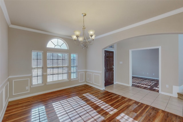 spare room with tile patterned flooring, ornamental molding, and a chandelier