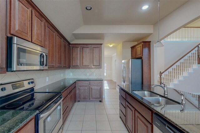 kitchen with sink, dark stone counters, decorative backsplash, light tile patterned floors, and appliances with stainless steel finishes