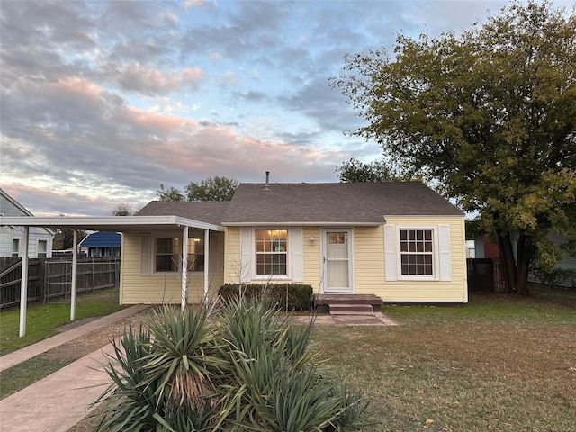 view of front of home with a carport and a lawn