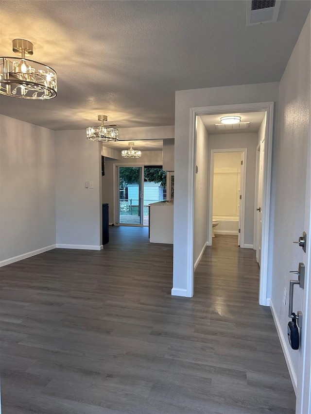 hallway featuring dark hardwood / wood-style floors and an inviting chandelier