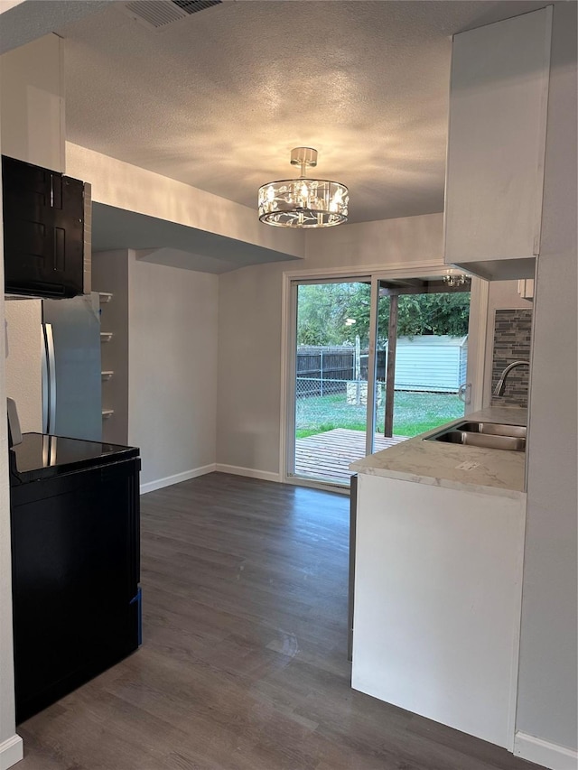 kitchen featuring stainless steel refrigerator, sink, an inviting chandelier, electric range oven, and dark hardwood / wood-style flooring