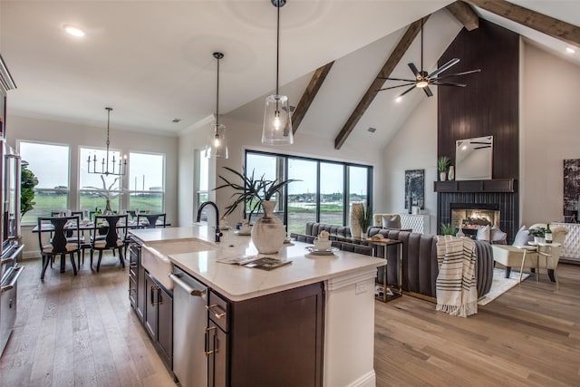 kitchen with dishwasher, a center island with sink, ceiling fan with notable chandelier, hanging light fixtures, and beamed ceiling