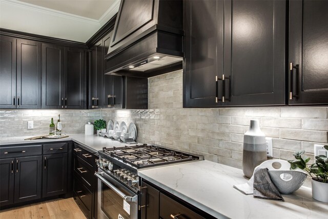 kitchen with backsplash, premium range hood, high end stainless steel range oven, and crown molding