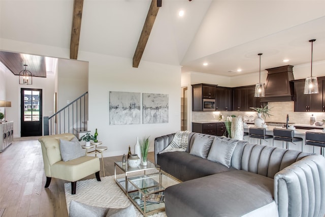 living room with beamed ceiling, a notable chandelier, light hardwood / wood-style floors, and high vaulted ceiling