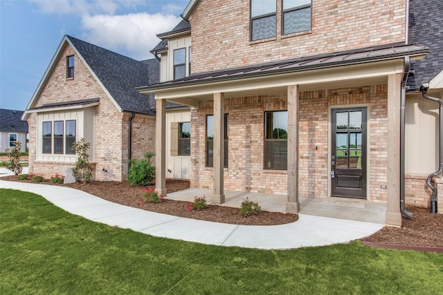 entrance to property with a lawn and covered porch