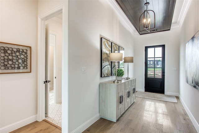 foyer featuring a chandelier, light wood-type flooring, and crown molding