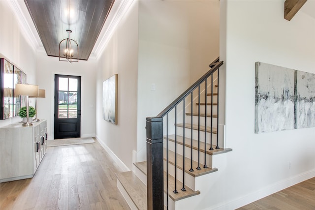 foyer entrance with light hardwood / wood-style floors, crown molding, and a notable chandelier