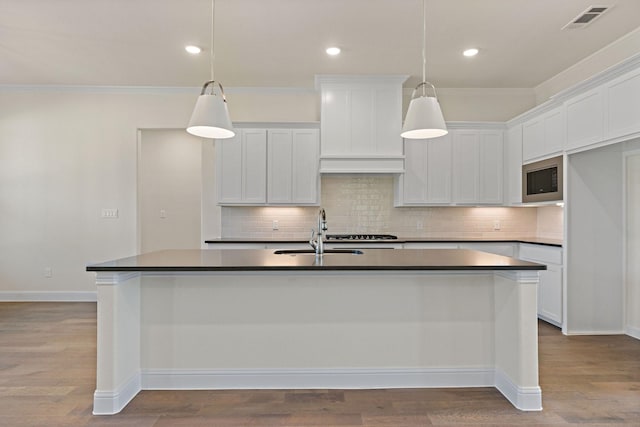 kitchen featuring white cabinetry, a kitchen island with sink, sink, and pendant lighting