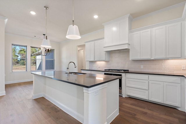 kitchen featuring premium range hood, sink, pendant lighting, a center island with sink, and white cabinets