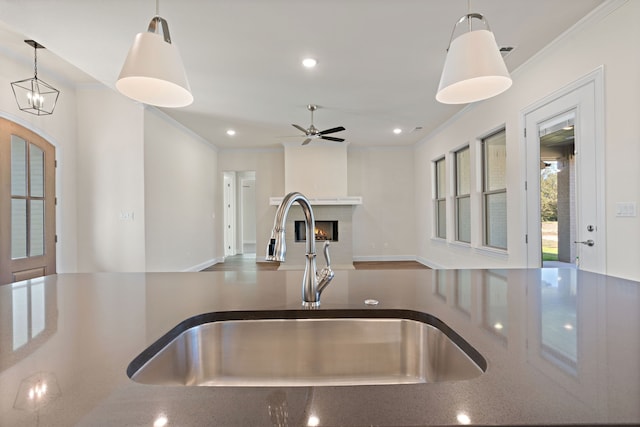 kitchen with ceiling fan with notable chandelier, decorative light fixtures, crown molding, and sink