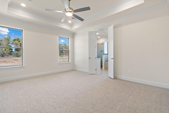 carpeted spare room with a tray ceiling, ornamental molding, and ceiling fan