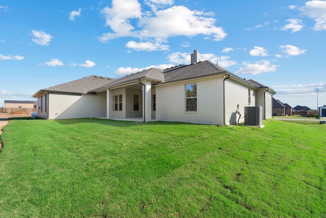 rear view of property with a yard, central AC, and a patio area