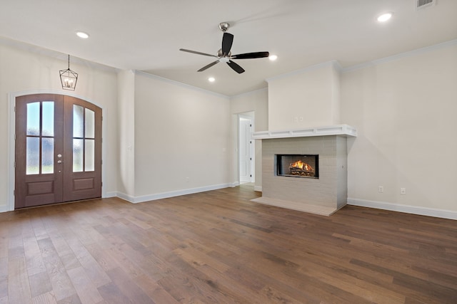 unfurnished living room featuring a fireplace, french doors, wood-type flooring, and ceiling fan with notable chandelier