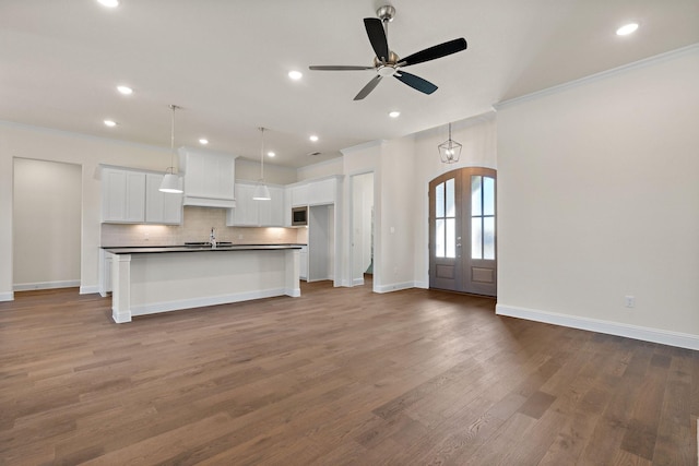 kitchen with french doors, ceiling fan, sink, a center island with sink, and white cabinets