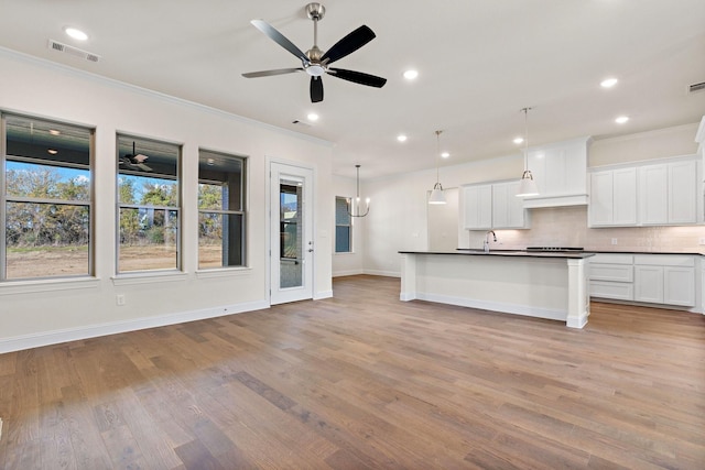 kitchen with pendant lighting, white cabinetry, a kitchen island with sink, and sink