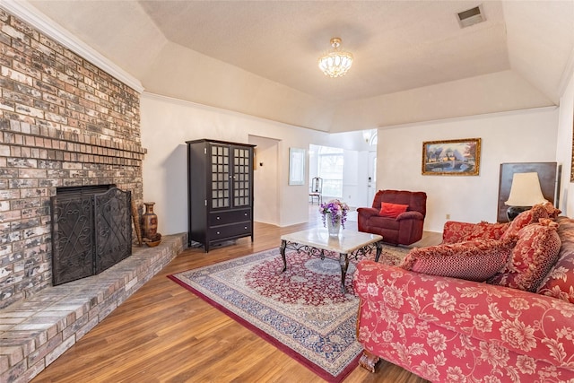 living room with a raised ceiling, a fireplace, hardwood / wood-style floors, and ornamental molding