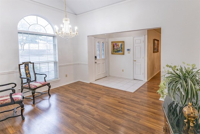 foyer with hardwood / wood-style floors, lofted ceiling, an inviting chandelier, and crown molding