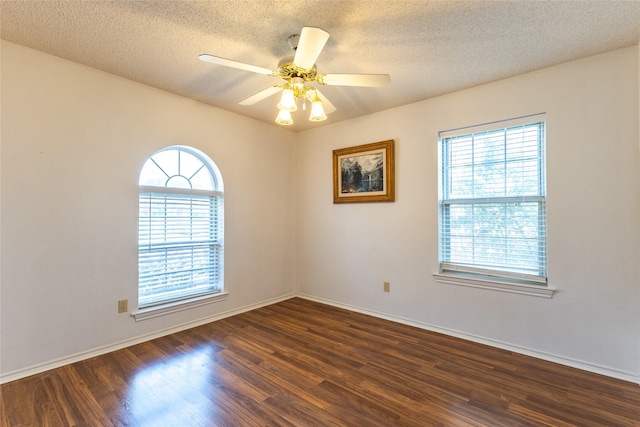 empty room with a textured ceiling, dark hardwood / wood-style flooring, ceiling fan, and a healthy amount of sunlight