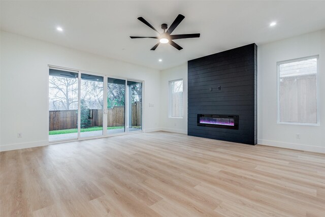 unfurnished living room with ceiling fan, a fireplace, and light wood-type flooring