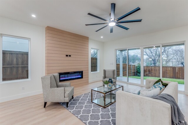 living room with ceiling fan, a large fireplace, and hardwood / wood-style flooring