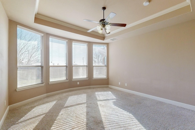 carpeted empty room with ceiling fan, ornamental molding, and a raised ceiling