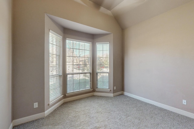 spare room featuring carpet and vaulted ceiling