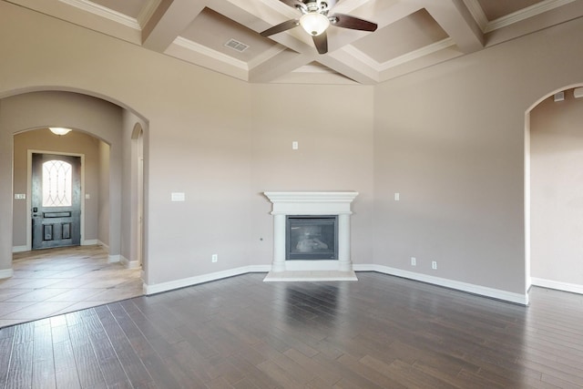 unfurnished living room with dark wood-type flooring, coffered ceiling, ceiling fan, ornamental molding, and beamed ceiling