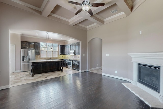 kitchen with stainless steel appliances, coffered ceiling, beamed ceiling, decorative light fixtures, and a kitchen island