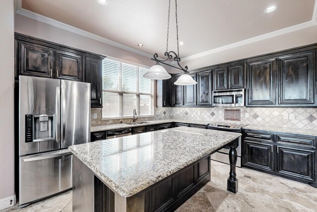 kitchen with light stone countertops, appliances with stainless steel finishes, sink, pendant lighting, and a kitchen island