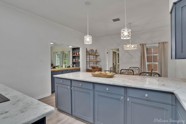 kitchen with pendant lighting, light hardwood / wood-style floors, light stone counters, and crown molding