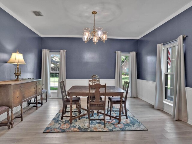 dining area with crown molding, light hardwood / wood-style flooring, and an inviting chandelier