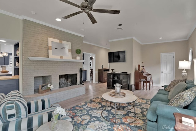 living room featuring ceiling fan, crown molding, light hardwood / wood-style floors, and a brick fireplace