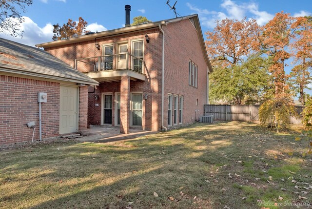 rear view of house with a yard, a balcony, and central air condition unit