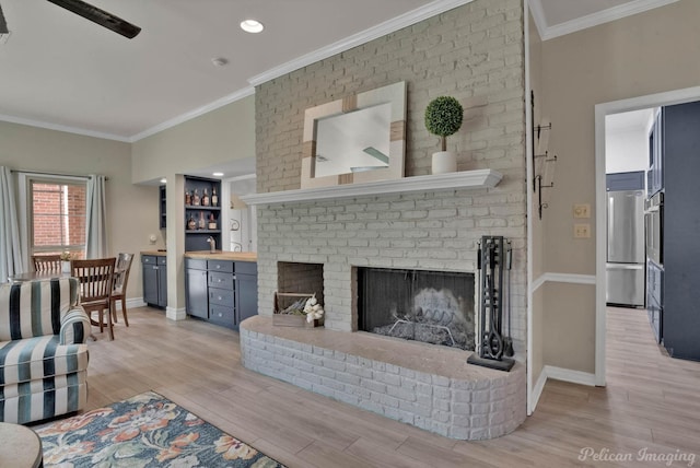 living room with a fireplace, light hardwood / wood-style floors, and ornamental molding