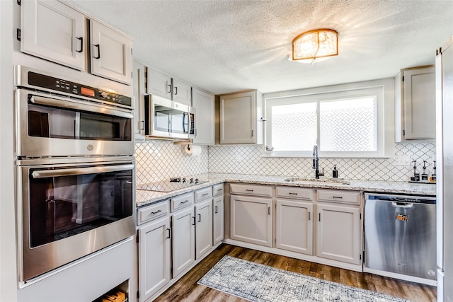 kitchen featuring dark wood-type flooring, light stone countertops, sink, and stainless steel appliances