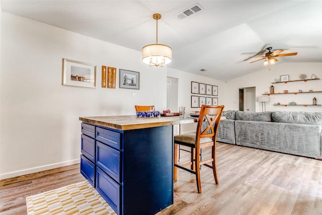 kitchen with wooden counters, a kitchen breakfast bar, blue cabinetry, light hardwood / wood-style flooring, and hanging light fixtures