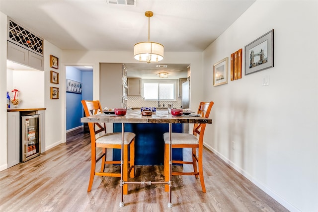 dining room with wine cooler and light wood-type flooring