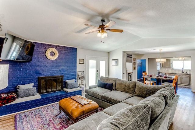 living room with a fireplace, sink, lofted ceiling, and light hardwood / wood-style flooring