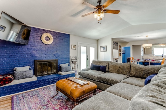 living room with a wealth of natural light, a fireplace, wood-type flooring, and vaulted ceiling