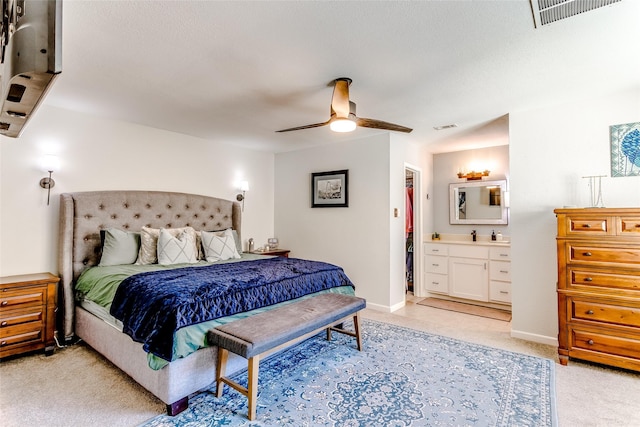 carpeted bedroom with ensuite bathroom and ceiling fan